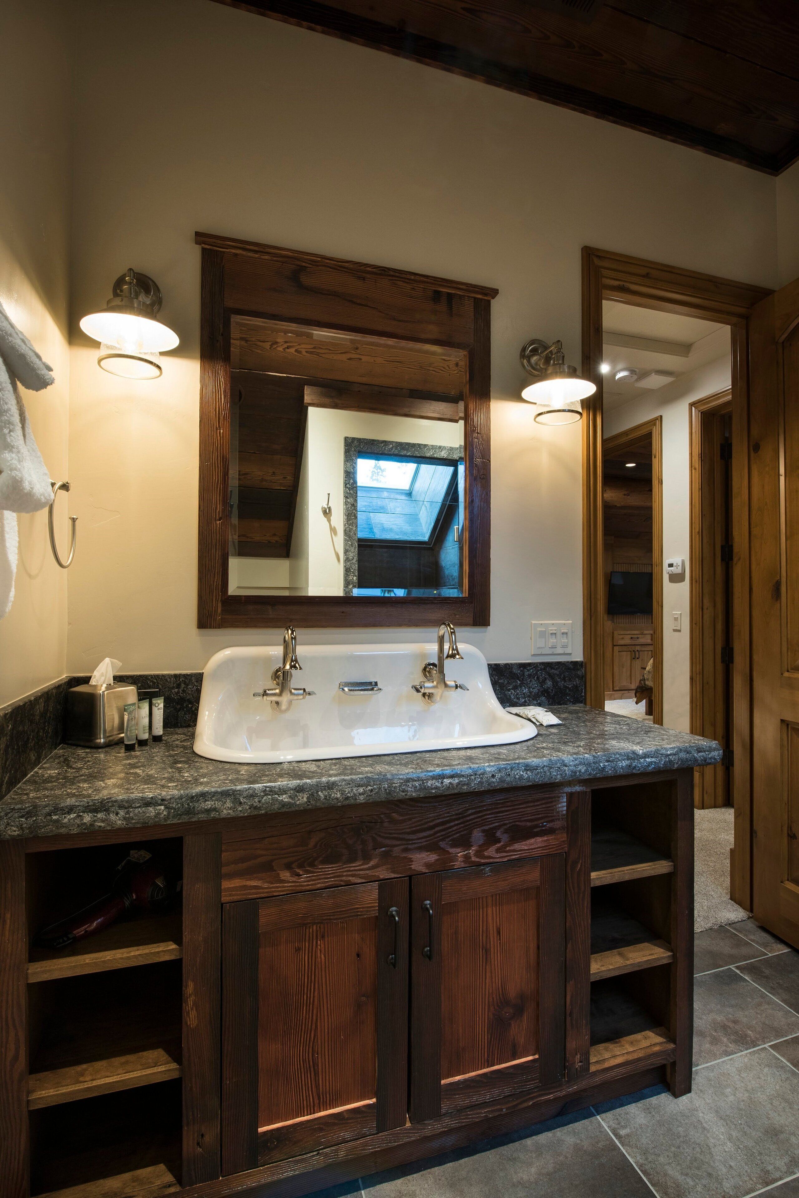 A bathroom with a large sink, wooden cabinets, and a mirror above it.