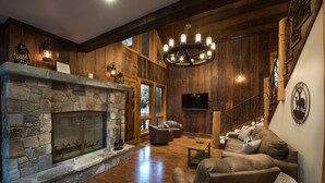 A cozy living room with a stone fireplace, leather sofas, and a chandelier. - Rustic Retreat (Yosemite National Park)