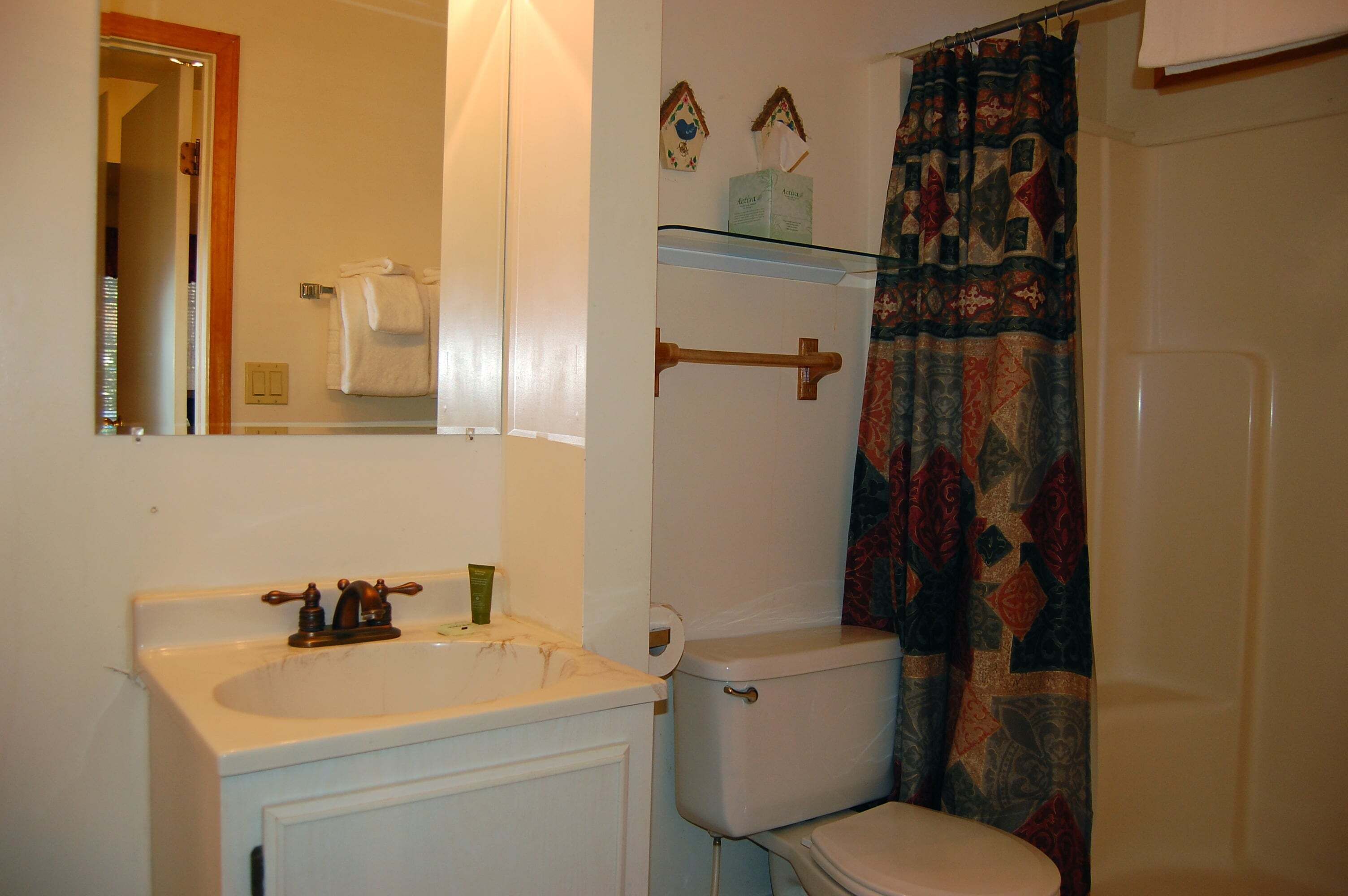A bathroom with a white sink, toilet, and shower curtain.