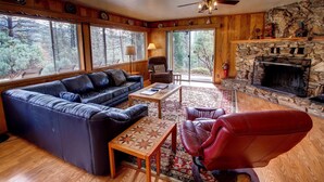 A cozy living room with a leather sofa, a red chair, a wooden coffee table, and a stone fireplace. - Longview (Yosemite National Park)