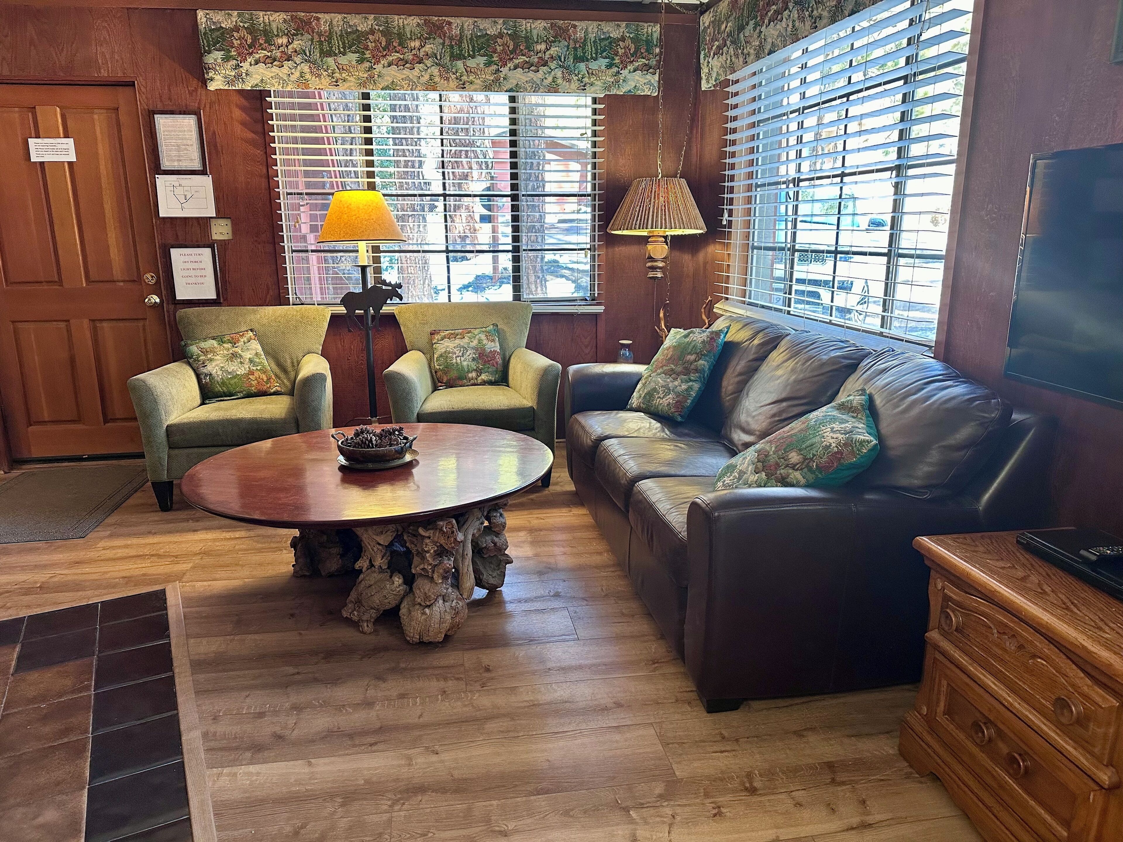 A cozy lobby with a wooden door, two armchairs, a sofa, a coffee table, and a television.