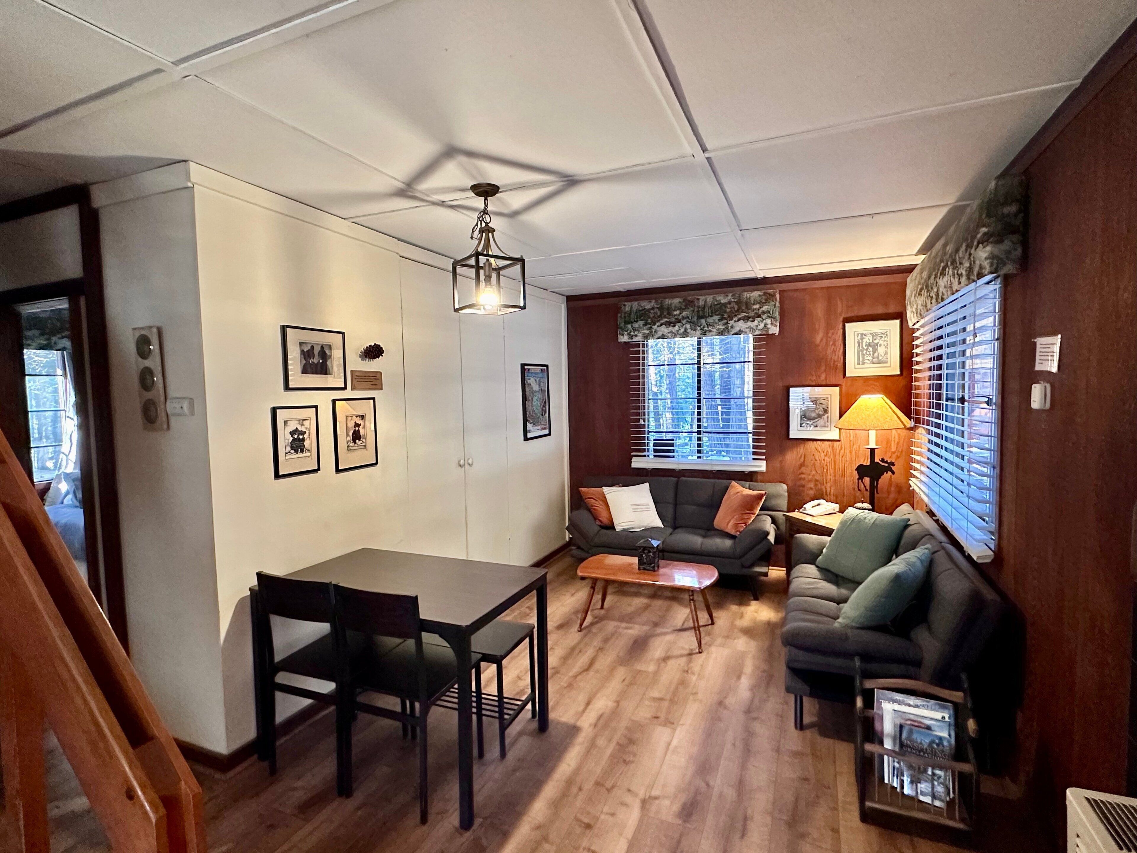 A cozy living room with a dining table, a sofa, and a lamp.