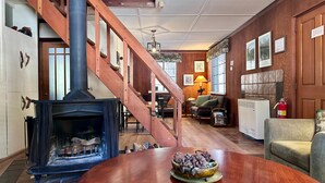 A cozy living room with a fireplace, a wooden staircase, a round table with a decorative bowl, and a sofa. - Heart of the Meadow (Yosemite National Park)