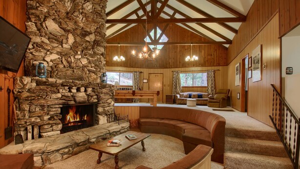 A cozy living room with a stone fireplace, wooden beams, and a comfortable seating area. - Villarreal Retreat (Yosemite National Park)
