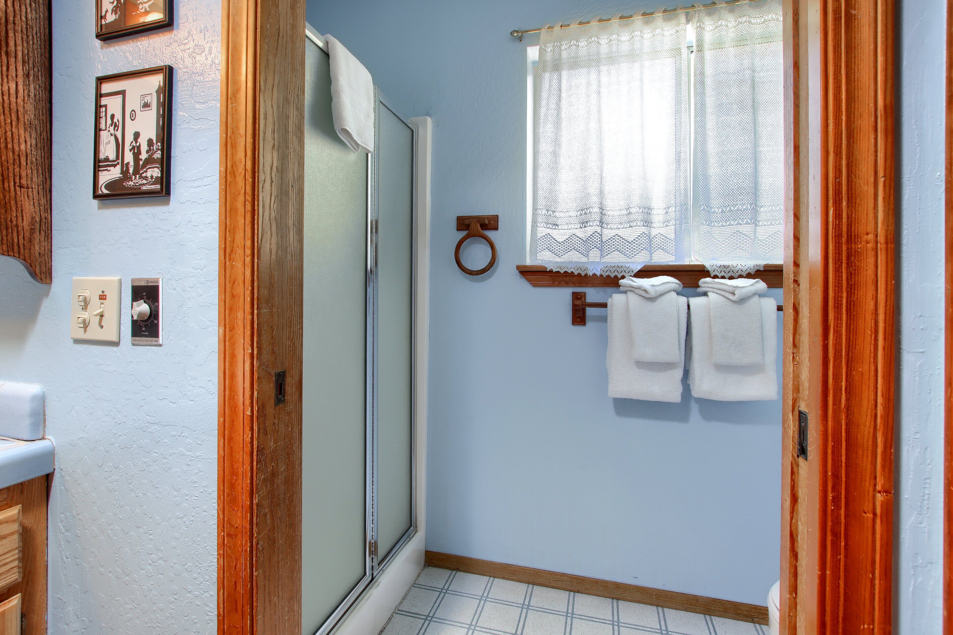 A bathroom with a shower, a toilet, a sink, and a window with a curtain.