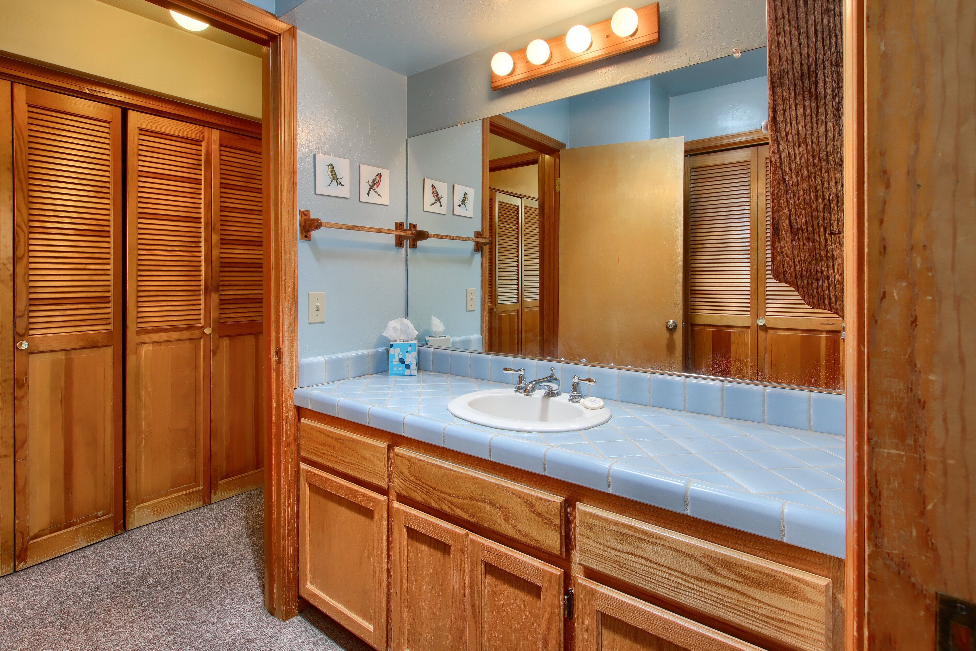 A bathroom with wooden cabinets, a sink, and a mirror.