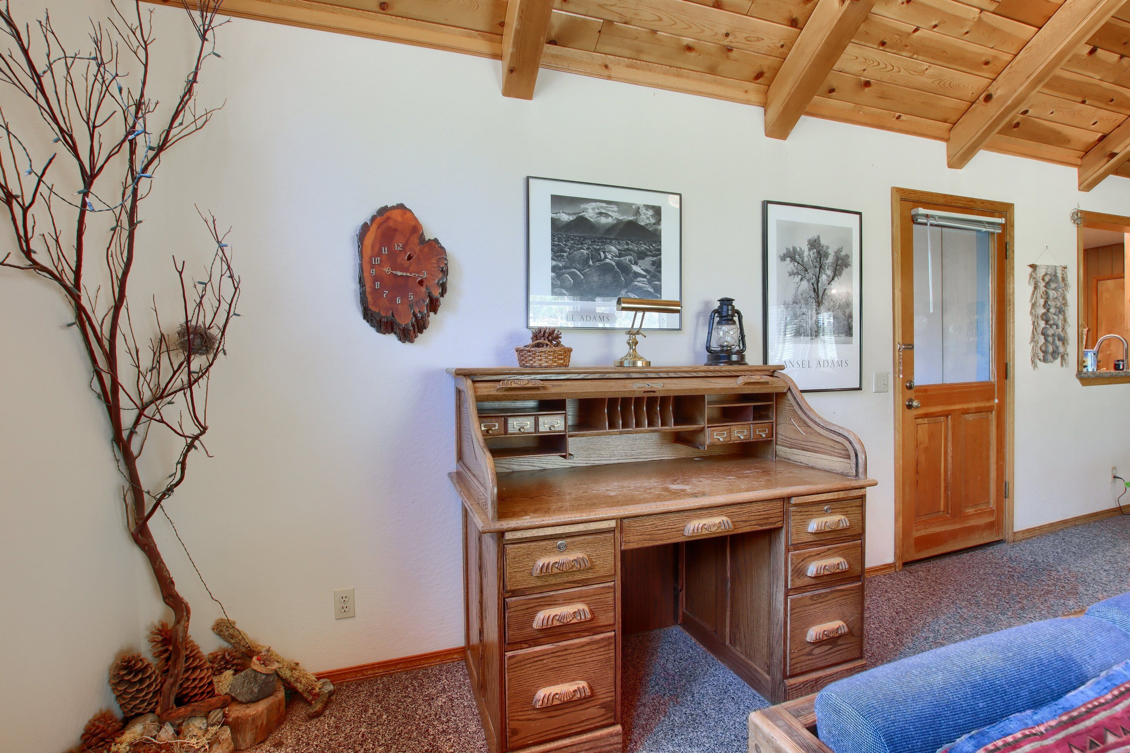 A wooden desk with drawers, a framed picture, and a lamp.