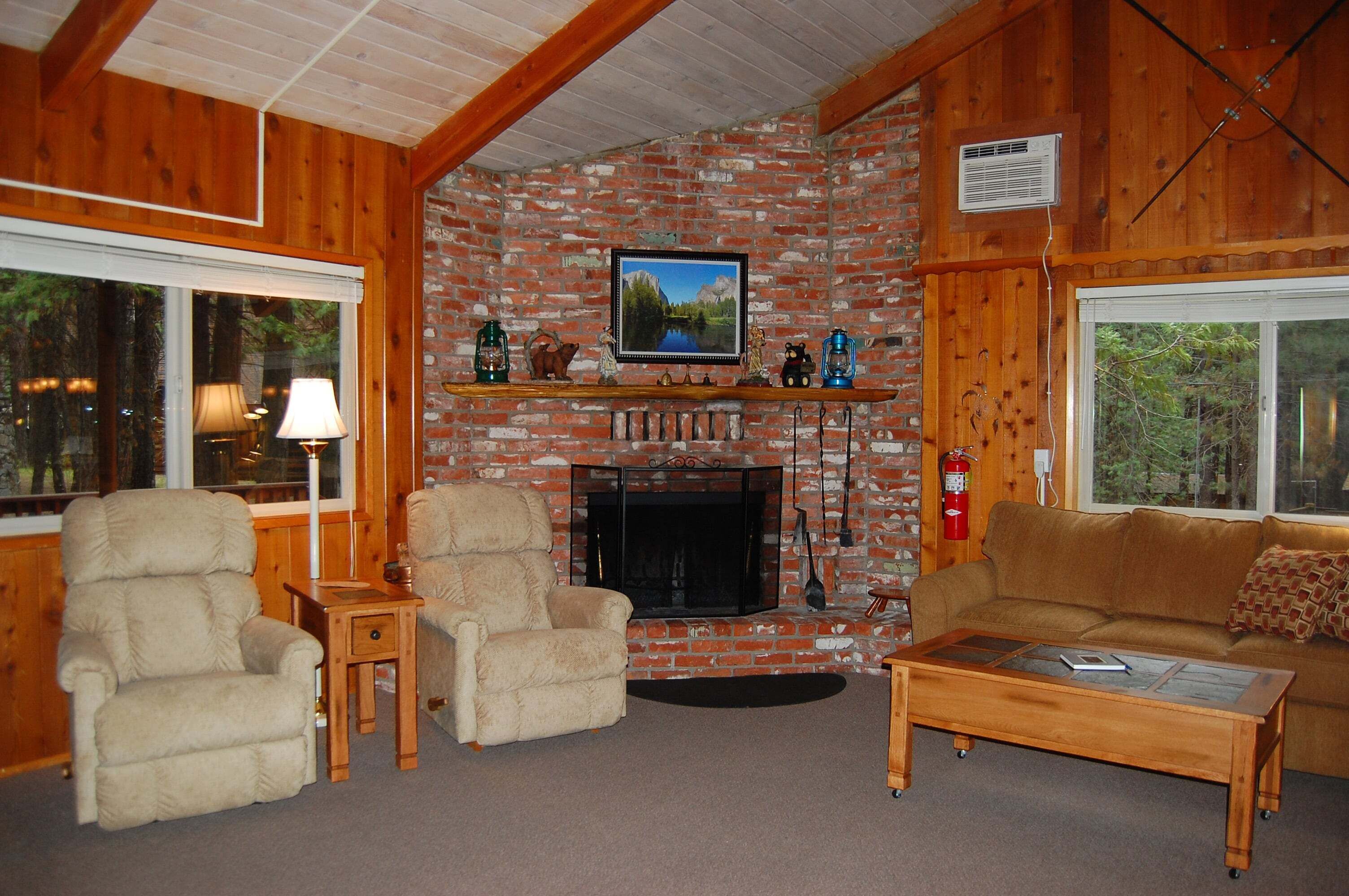 A cozy living room with a fireplace, wooden furniture, and a television mounted above it.