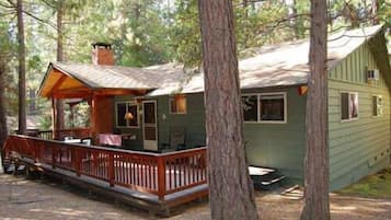 A cabin with a porch, a chimney, and a deck.