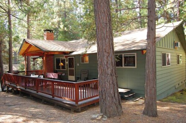 A cabin with a wooden deck, a covered porch, and a chimney. - Dunning's Retreat (Yosemite National Park)