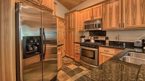 A kitchen with wooden cabinets, stainless steel appliances, granite countertops, and a checkered tile floor. - The Tree House (Yosemite National Park)