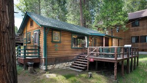A rustic log cabin with a porch and steps leading to the entrance. - Chipmunk Hollow (Yosemite National Park)