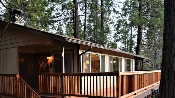 A cabin with a wooden deck, large windows, and a chimney. - Sequoia House (Yosemite National Park)