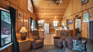 A cozy cabin interior with wooden walls, a dining area, and a kitchen. - Wawona Cabin (Yosemite National Park)