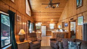 A cozy cabin interior with wooden walls, a dining area, and a living room with a sofa and armchairs. - Wawona Cabin (Yosemite National Park)