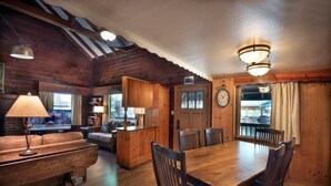 A cozy cabin interior with a wooden dining table, chairs, a sofa, and a bar area. - Grandma's Cabin (Yosemite National Park)