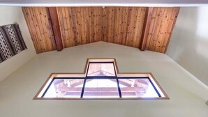 Una habitación con techo inclinado, paneles de madera y un tragaluz con diseño geométrico.