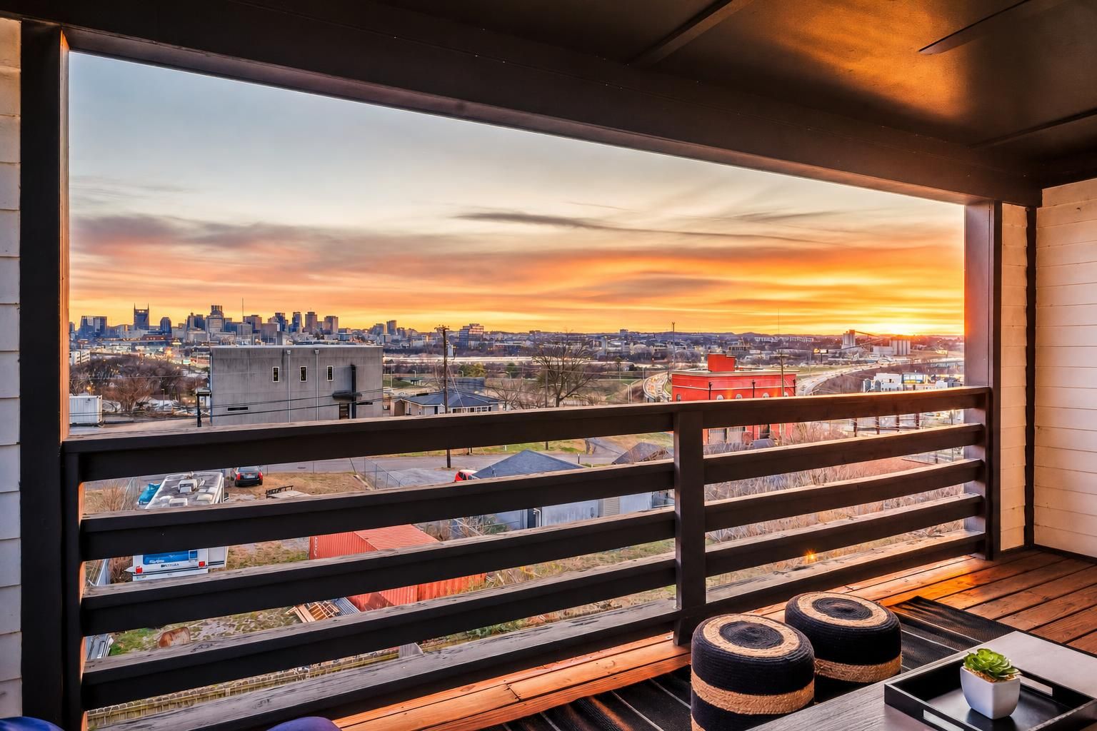 A balcony with a view of a city skyline at sunset.