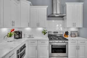 A modern kitchen with white cabinetry, a stainless steel range, and a built-in oven. - Nashville home with game room, 3 balconies & backyard, sleeps 12 (Nashville)
