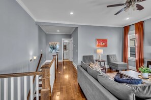 A living room with a grey sofa, a coffee table, and a ceiling fan. - Nashville home with game room, 3 balconies & backyard, sleeps 12 (Nashville)
