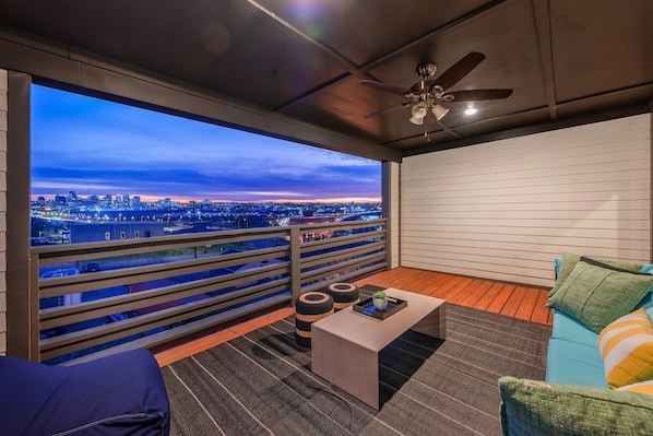 A balcony with a city view, a ceiling fan, and a seating area with cushions and a coffee table. - Nashville home with game room, 3 balconies & backyard, sleeps 12 (Nashville)