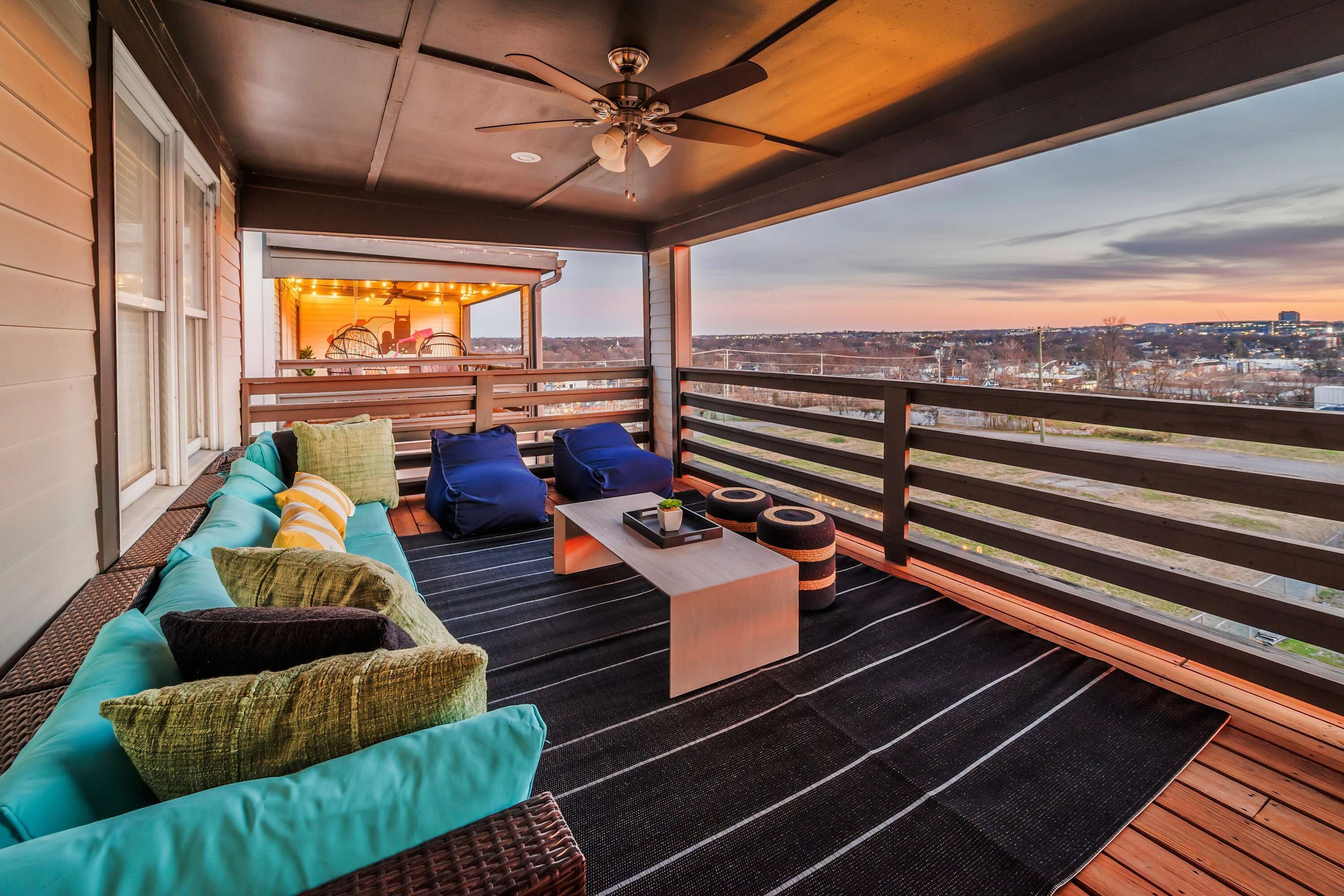 A balcony with a sofa, cushions, a coffee table, and a view of the cityscape.