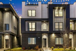 A modern multi-story residential building with a symmetrical facade, large windows, and a well-lit entrance. - Nashville bachelorette house with hot tub, karaoke stage & game room, sleeps 13 (Nashville)