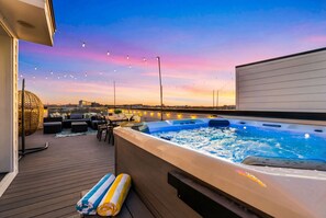 A rooftop terrace with a hot tub, seating area, and string lights against a sunset sky. - Nashville hot tub & karaoke game room home, sleeps 13, 4 bedrooms (Nashville)