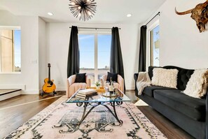 A living room with a glass coffee table, two sofas, a guitar, and a bull skull decoration. - Nashville bachelorette house with hot tub, karaoke stage & game room, sleeps 13 (Nashville)