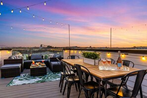 An outdoor seating area with a wooden table and chairs, a sofa, and a small plant. - Nashville weekend house with hot tub, karaoke & game room, sleeps 12 (Nashville)