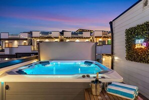 A hot tub with a neon sign, surrounded by modern buildings and string lights. - Nashville weekend house with hot tub, karaoke & game room, sleeps 12 (Nashville)