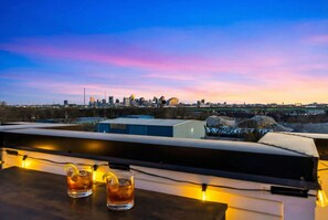A city skyline at dusk with a table featuring two glasses of a beverage. - Nashville hot tub & game room house, sleeps 13 on VRBO (Nashville)