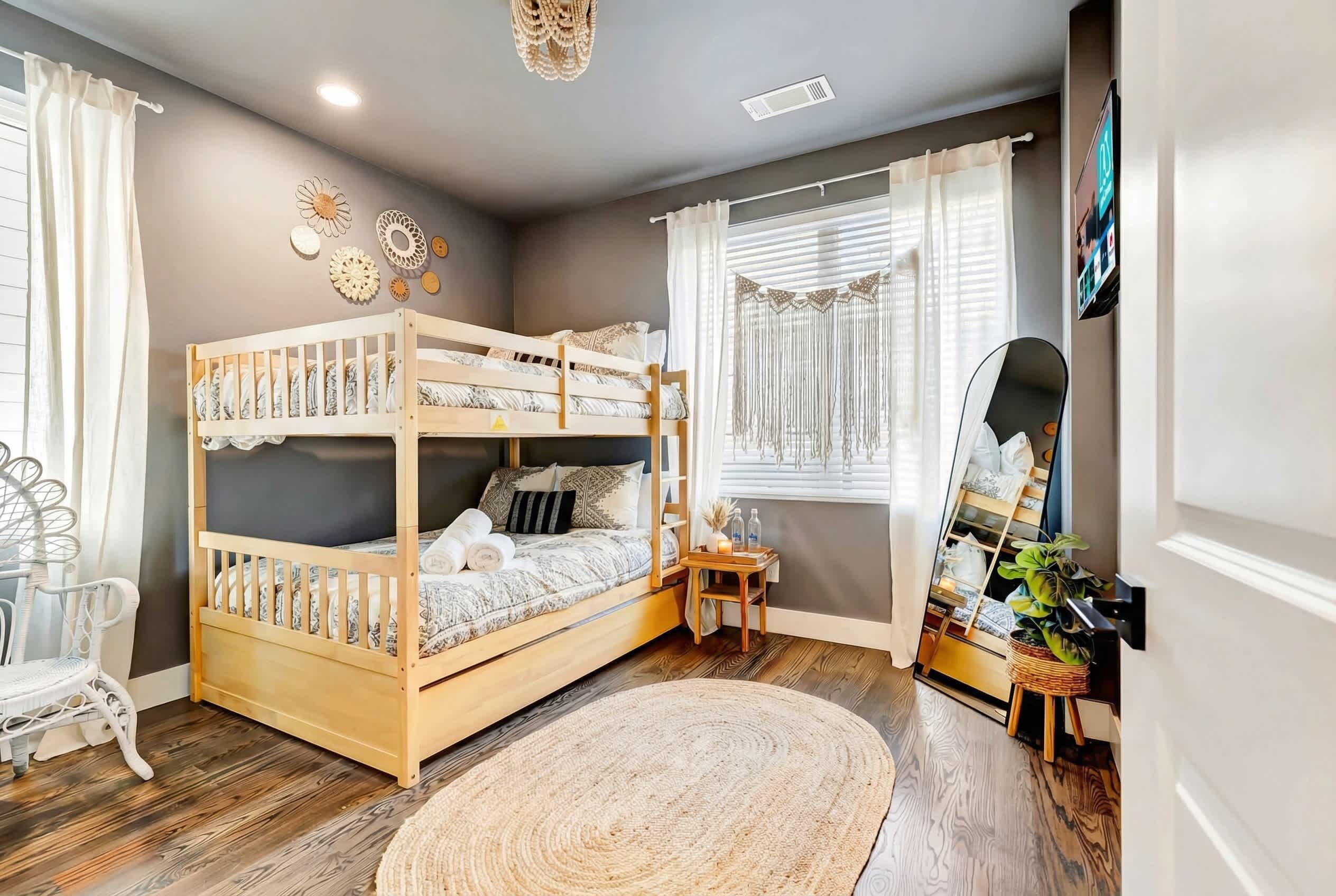Une chambre confortable avec un lit superposé, une petite table de chevet, une chaise, un tapis tissé et un miroir au mur.