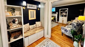 A living room with a dark accent wall, a bench with cushions, a fireplace, and a television.