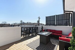 Eine Dachterrasse mit Holzboden, Sitzgelegenheiten im Freien und Blick auf die Stadtlandschaft.