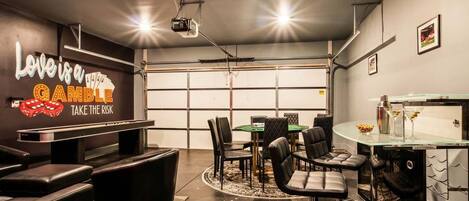 A modern bar area with a pool table, bar stools, and a glass-top bar counter.