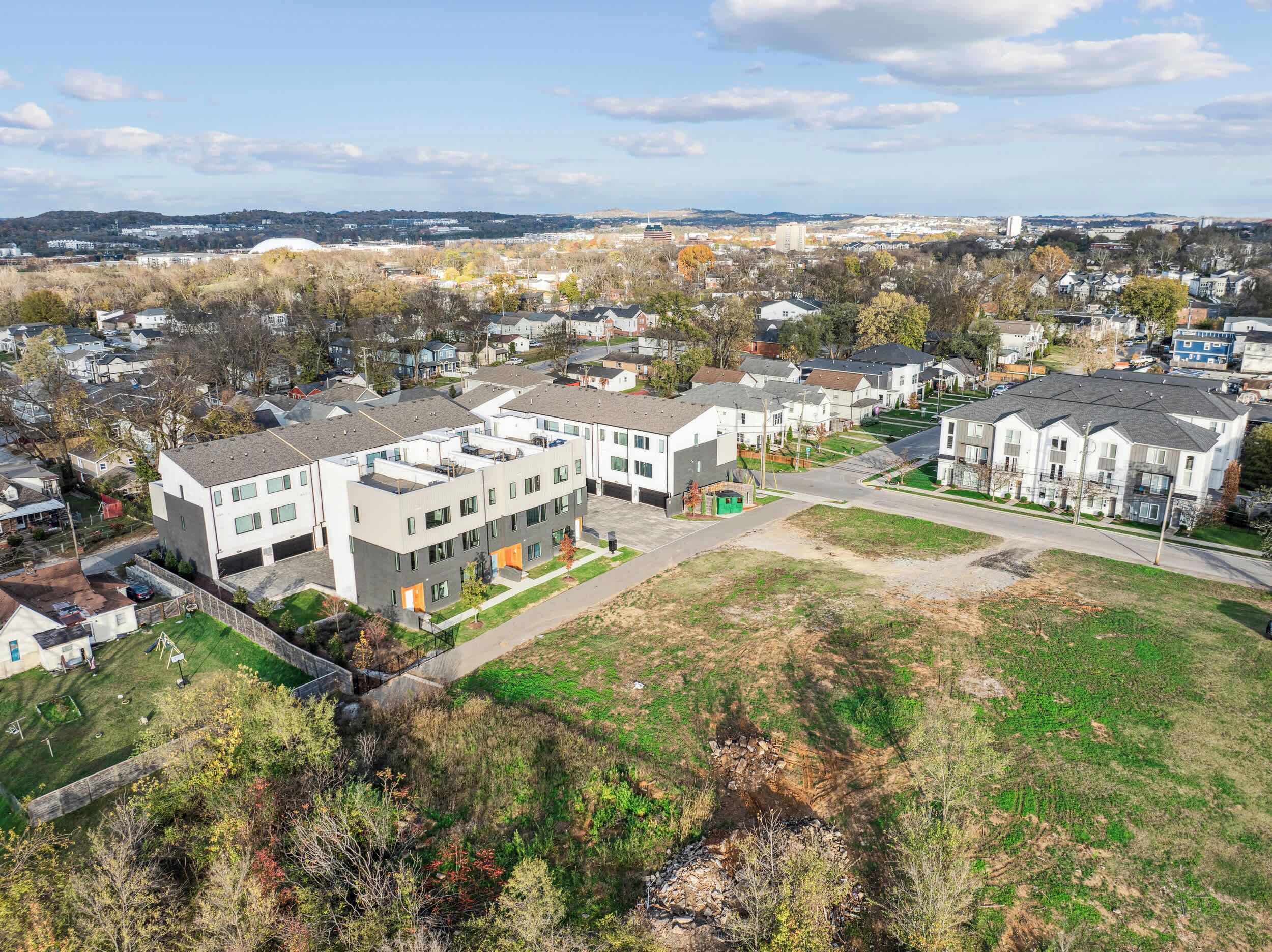 A modern apartment complex with multiple buildings, a central courtyard, and a view of the surrounding neighborhood.