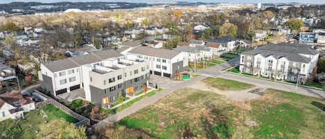 Ein moderner Apartmentkomplex mit mehreren Gebäuden, einem zentralen Innenhof und Blick auf die umliegende Nachbarschaft.