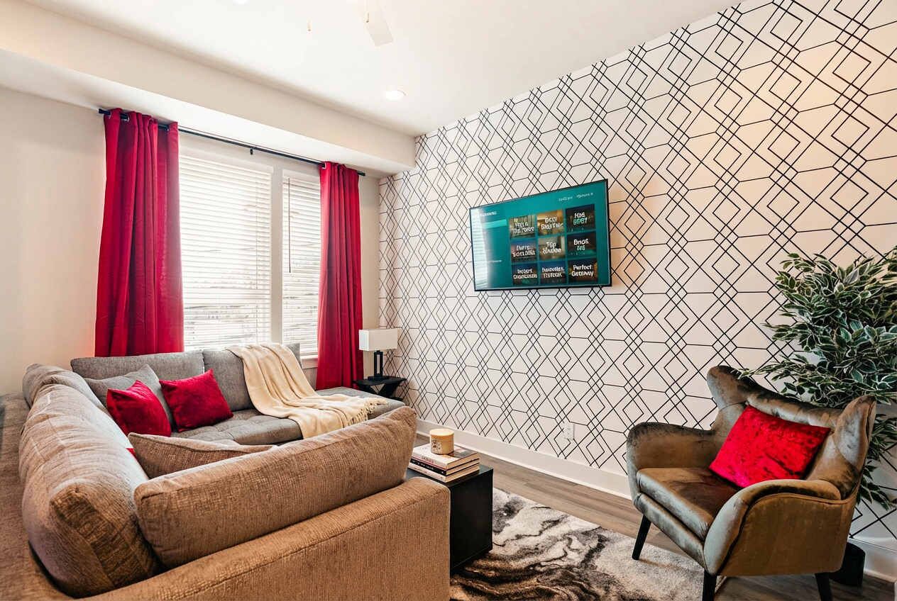 Una sala moderna con un sofá modular, un sillón individual, un televisor de pantalla plana montado en la pared y un papel tapiz estampado.