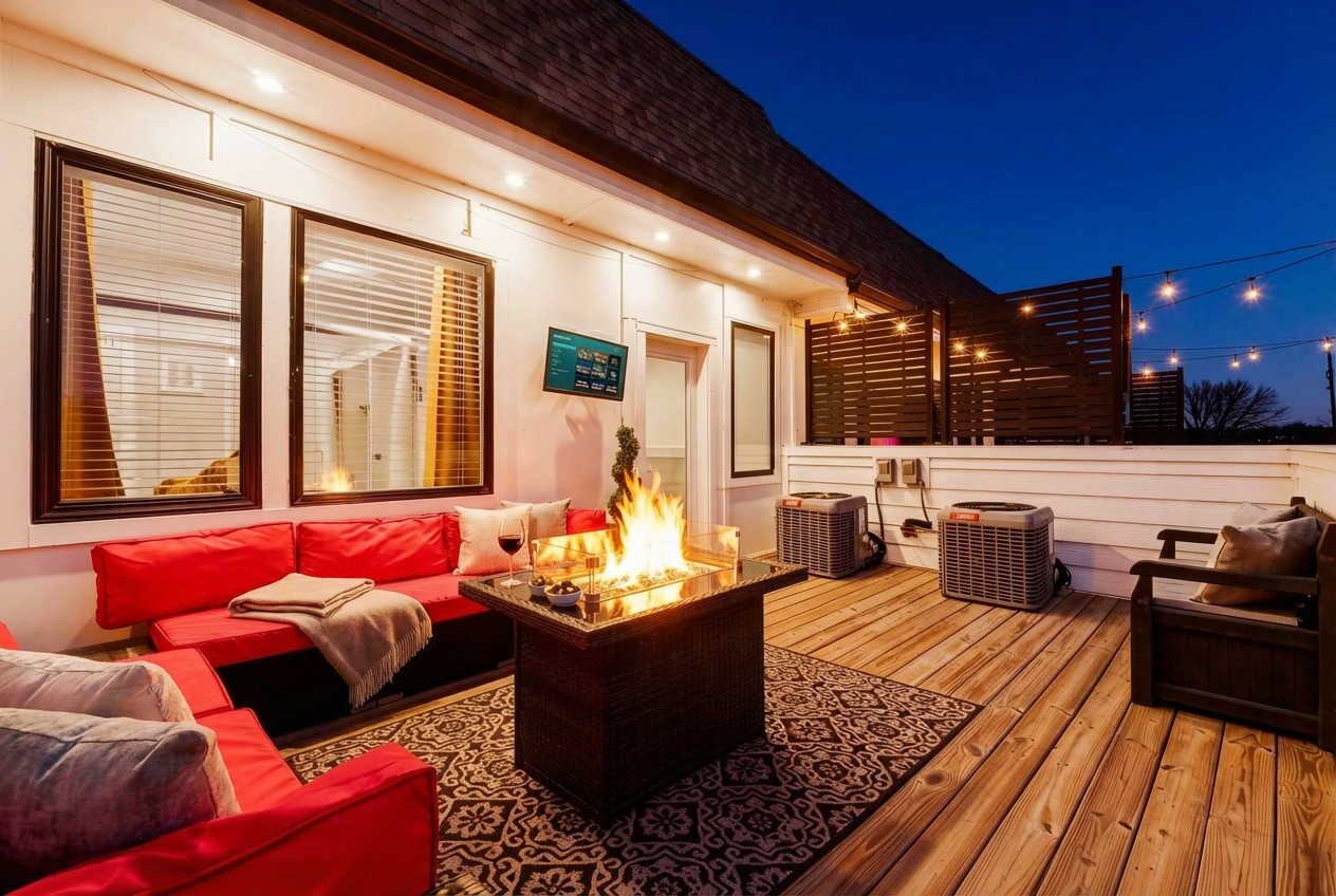 Un espacio al aire libre acogedor con una chimenea, una terraza de madera y luces colgantes.