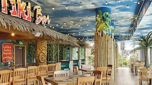 A restaurant with a tropical theme, including a thatched roof and a mural of a palm tree on the ceiling. - Downtown ATL Presidential Suite, Near Benz Stadium (Atlanta)