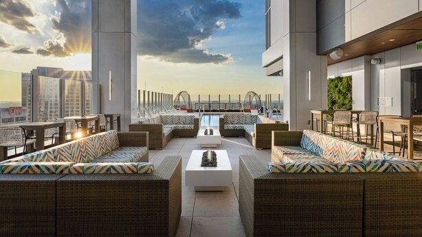 A rooftop lounge with wicker furniture, a central coffee table, and a view of the city skyline. - Downtown ATL Presidential Suite, Near Benz Stadium (Atlanta)
