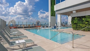 A modern pool area with lounge chairs and a glass wall with greenery. - Downtown ATL Presidential Suite, Near Benz Stadium (Atlanta)