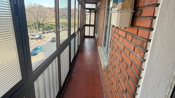 A corridor with large windows, a brick wall, and a metal railing. - ApartaHotel Achicoria (Madrid)