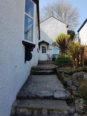 A white building with a stone staircase leading to a door marked "GARDEN". - Cosy garden cottage style flat with patio views (Grange-over-Sands)
