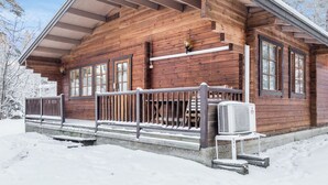 Puinen mökki, jossa on katettu kuisti ja keskusilmastointilaite.