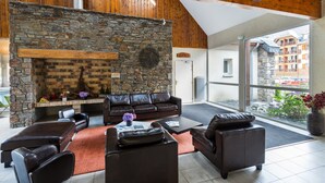 Una sala de estar acogedora con chimenea de piedra, mobiliario de cuero y vistas al pueblo.