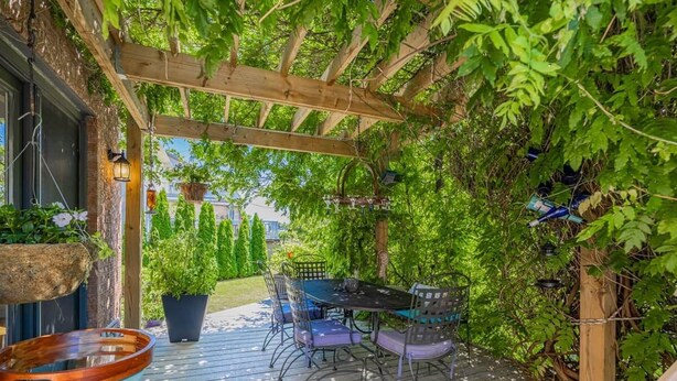 Une terrasse en bois agrémentée d’une pergola, de meubles d’extérieur et de plantes en pot.