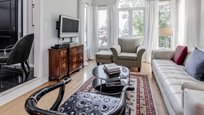 Un salon spacieux avec une grande fenêtre, un téléviseur, un canapé, une table basse et un fauteuil.