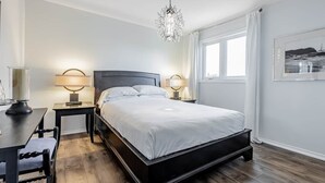 Une chambre moderne avec un grand lit, des tables de chevet, un bureau et un lustre.